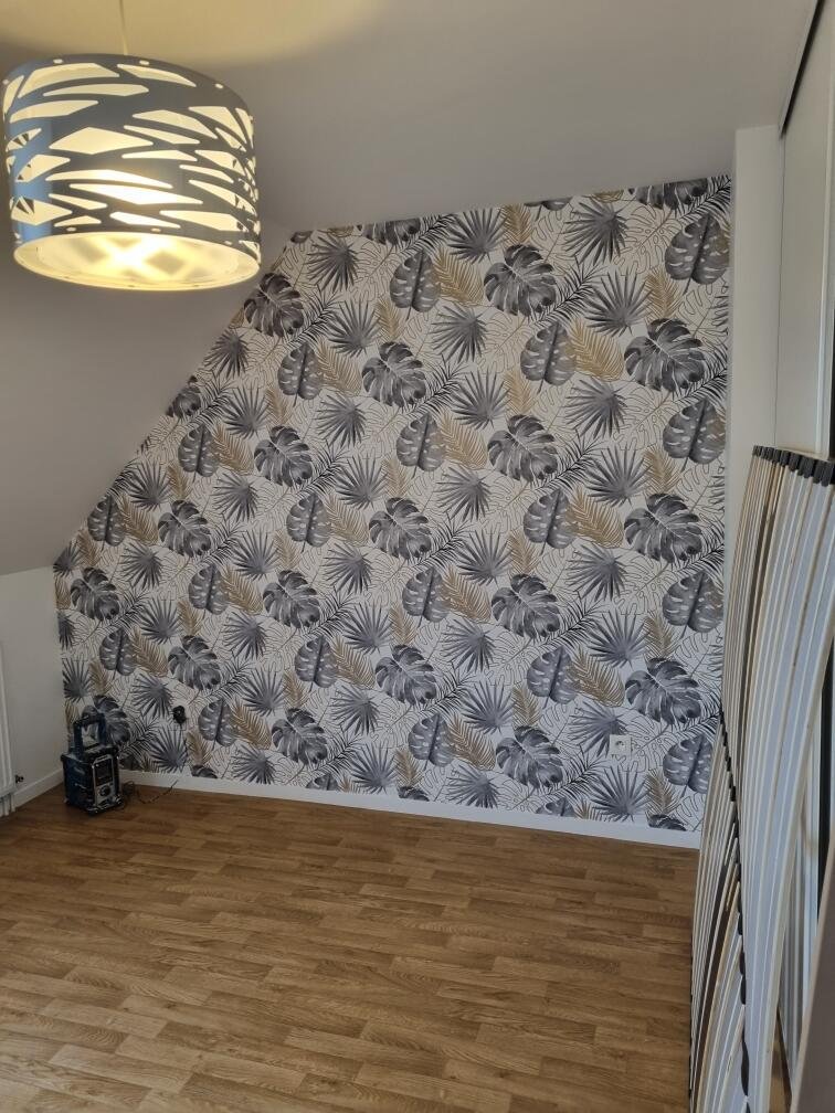 Mur avec du papier peint à motifs de feuilles grises, blanches et doré sur un fond blanc