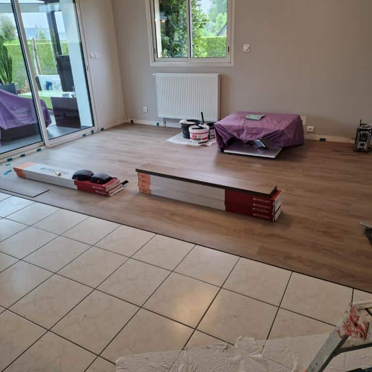 Image montrant la transition entre un ancien carrelage beige et un nouveau sol en parquet clair
